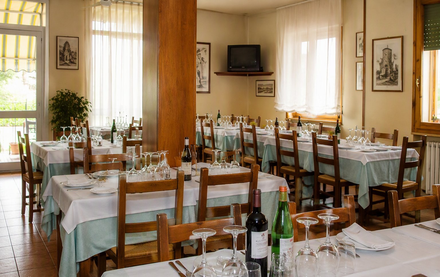 La sala grande con le tovaglie chiare e i quadri alle pareti